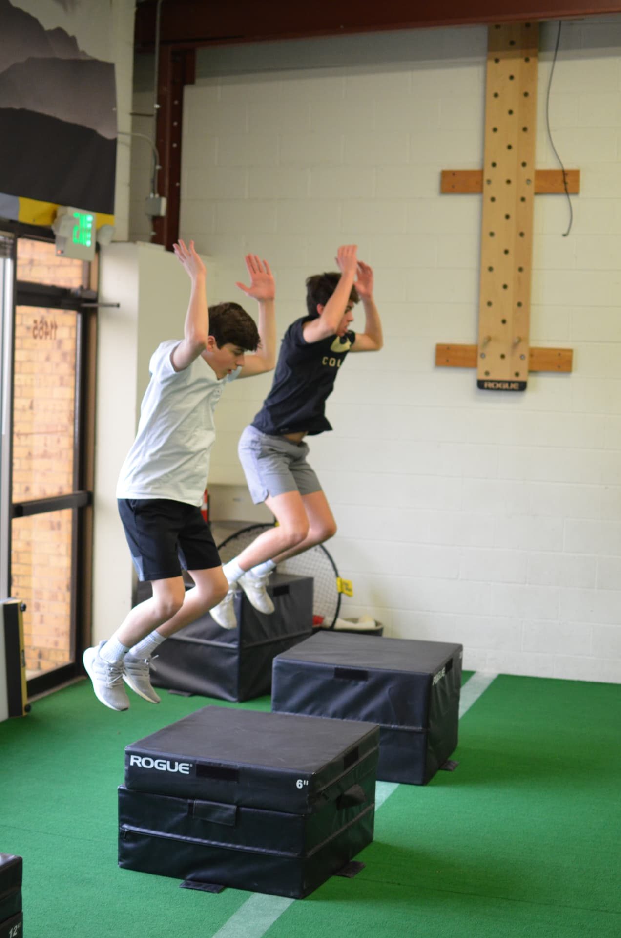 Two young athletes jumping onto plyo boxes at ETHOS