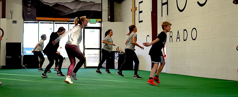Group of young ETHOS athletes moving through a warm-up on the turf